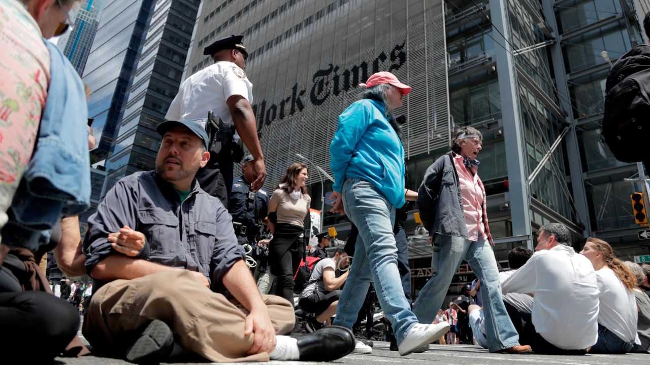 Activists sit on an intersection as others are taken into custody by New York Police officers during a climate change rally outside of the New York Times building.