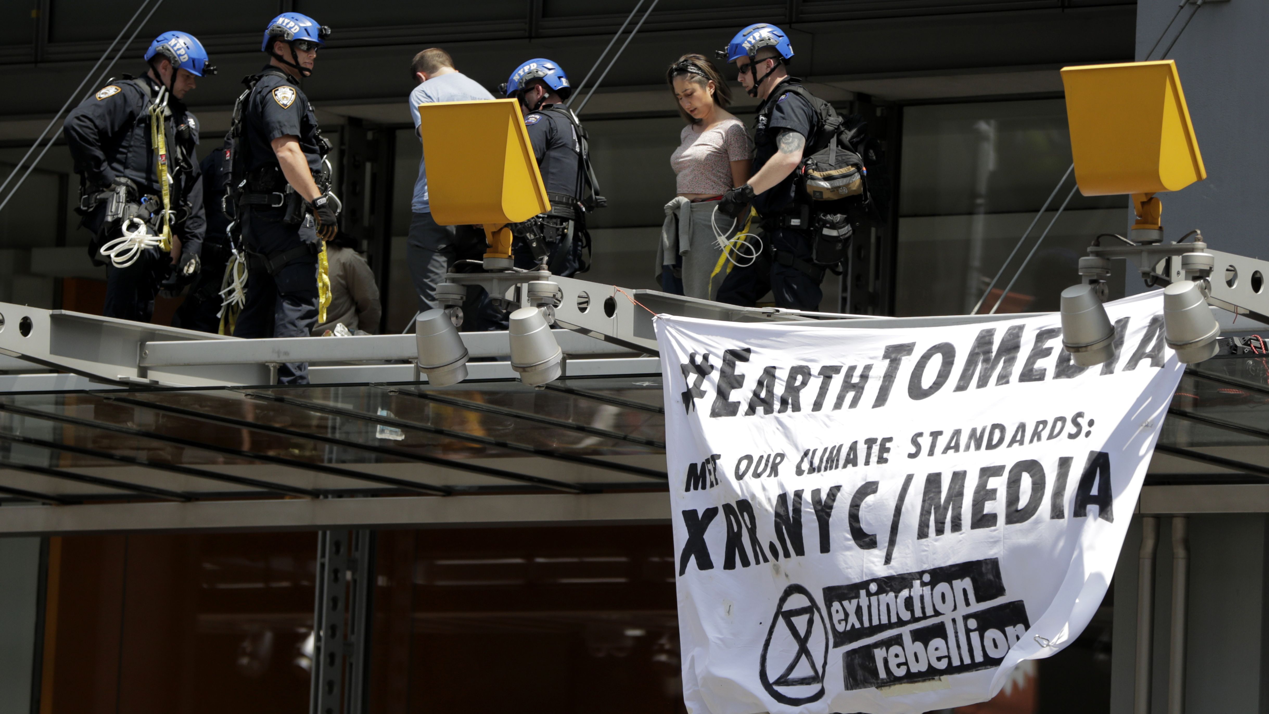 New York Police officers take into custody activists who climbed on the awning of the New York Times building to hang signs during a climate change rally, Saturday, June 22, 2019, in New York.