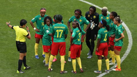 Cameroon players confront referee Qin Liang following England's second goal for Ellen White which is allowed after a VAR decision.