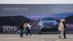 People walk past a giant billboard advertising German car manufacturing giant Daimler's annual general meeting on May 22, 2019 in Berlin. - Daimler boss Dieter Zetsche, 66, bows out after 13 years on with his Swedish successor Ola Kallenius needing to tackle problems brewing under the bonnet of the Mercedes-Benz maker. (Photo by John MACDOUGALL / AFP)        (Photo credit should read JOHN MACDOUGALL/AFP/Getty Images)