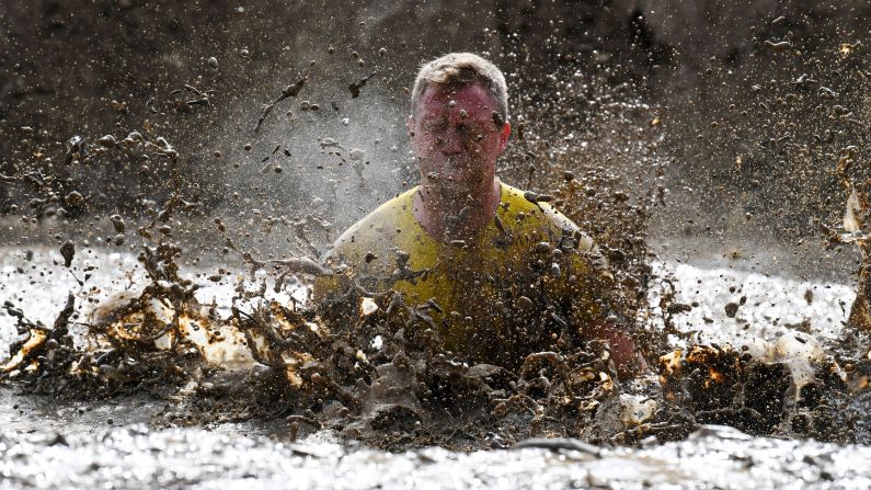 A runner jumps in a mud pit as he takes part in the Mud Day, a 13km race with obstacles in Beynes, France on June 16.