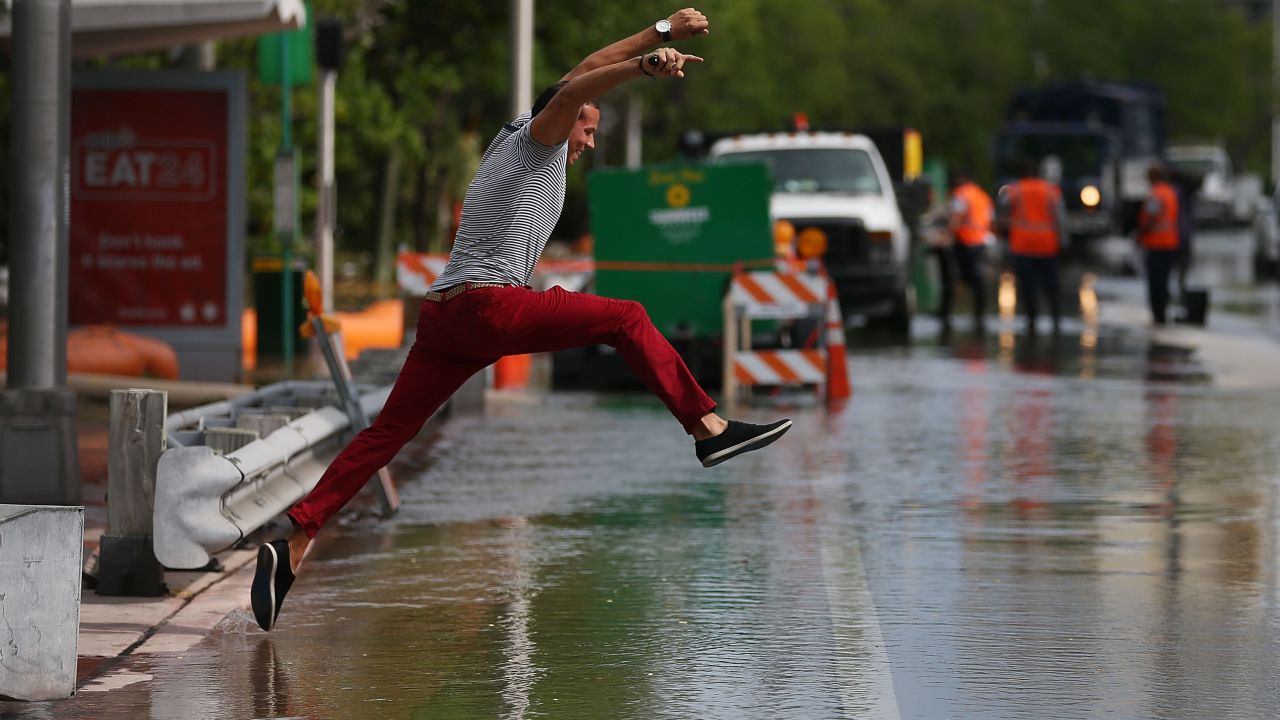 A man tries to jump to a shallow spot while crossing a flooded street on Miami Beach during the 2015 king tide floods.
