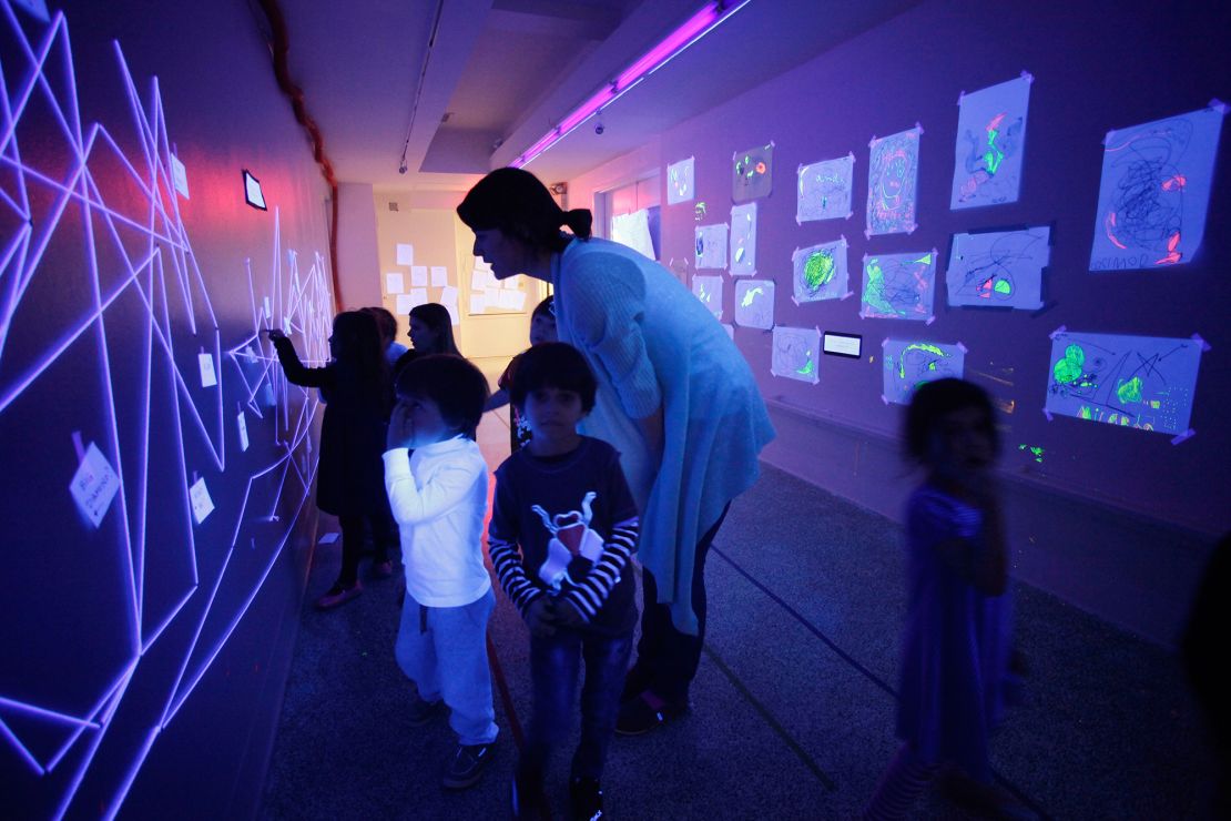 A teacher at the Blue School in New York leads students in a discussion about artwork illuminated by ultraviolet lamps in 2011.