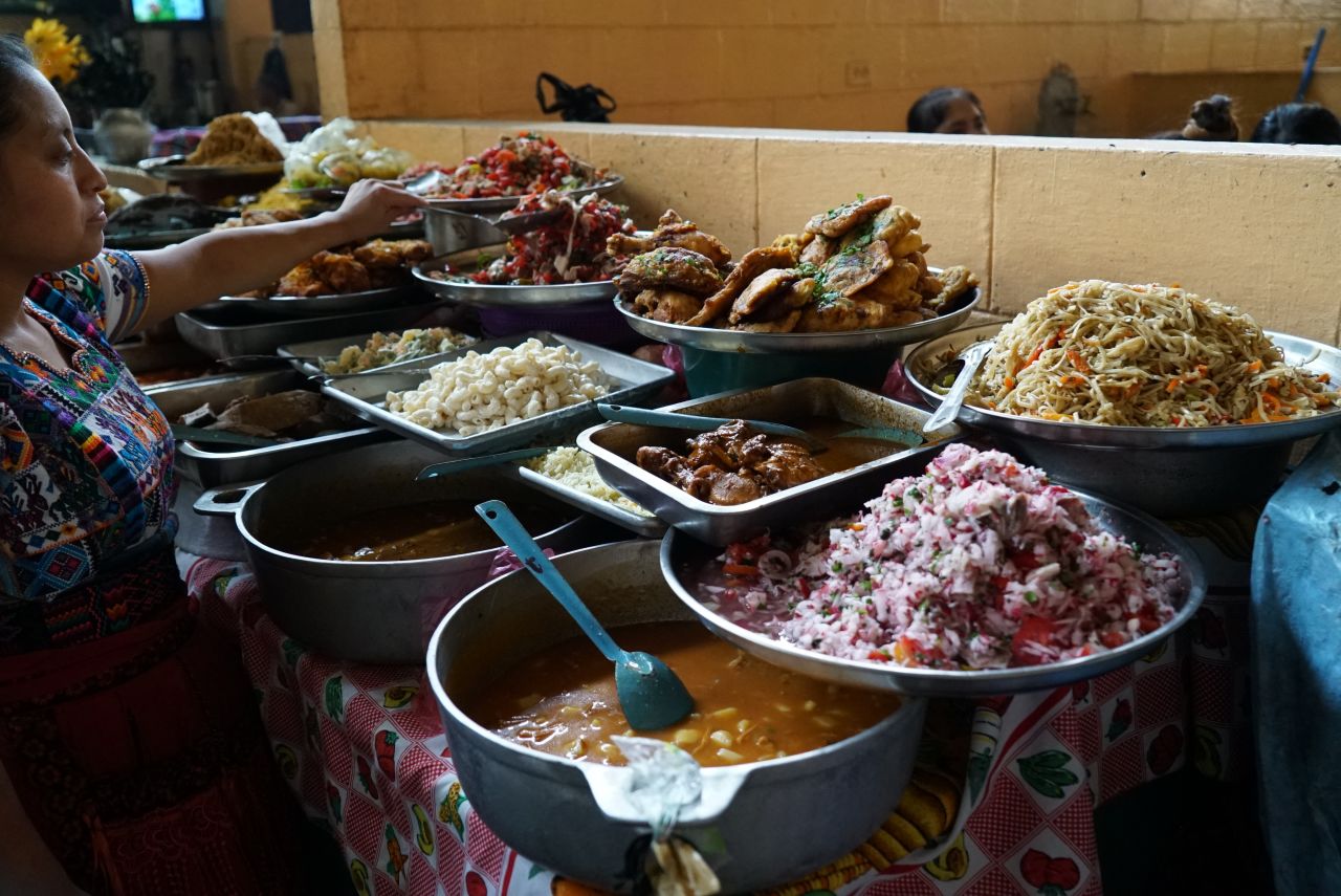 <strong>Mealtime:</strong> A local woman watches over a food stall where she's selling a number of dishes, including pepián, plantain and caldo de res (beef broth).
