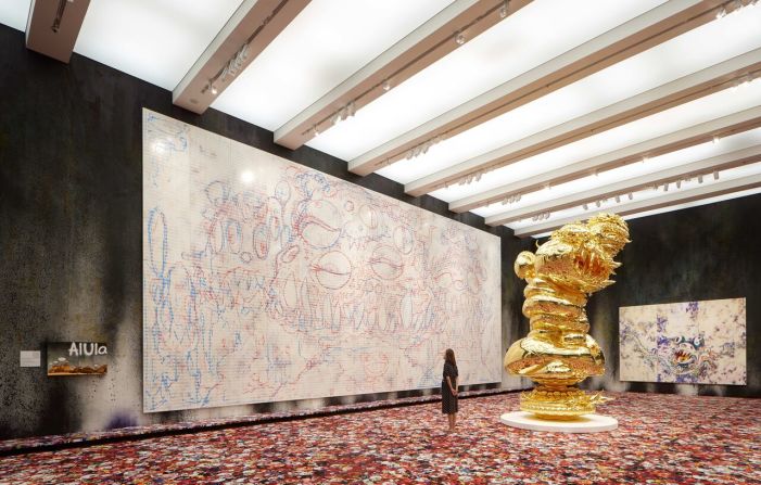 A 4.5 meter-tall gold-leaf clad sculpture called "The Birth Cry of a Universe" dominates the third floor of the exhibit. The massive piece, shown here in front of acrylic paintings "AIUIa" (2019) and AIUIa DOB" (2019), is being exhibited for the first time after over a decade of work.