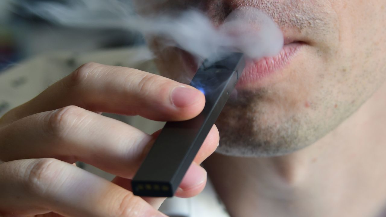 An illustration shows a man exhaling smoke from an electronic cigarette in Washington, DC on October 2, 2018. - In just three years, the electronic cigarette manufacturer Juul has swallowed the American market with its vaporettes in the shape of a USB key. Its success represents a public health dilemma for health authorities in the United States and elsewhere. (Photo by EVA HAMBACH / AFP)        (Photo credit should read EVA HAMBACH/AFP/Getty Images)