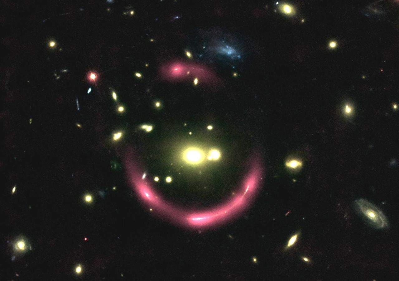These are magnified galaxies behind large galaxy clusters. The pink halos reveal the gas surrounding the distant galaxies and its structure. The gravitational lensing effect of the clusters multiplies the images of the galaxies.