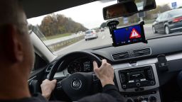 A test driver drives a car which is connected to another car via smart phone during a demonstration on Autobahn A9 near Pfaffenhofen, Germany, 09 November 2015. A display which is attached to the windshield shows a warning signal along the words 'Slow down'. German Minister of Transport and Digital Infrastructure Dobrindt and car experts introduced two pilot projects which demonstrated how the connection of vehicles via smartphone can improve traffic safety. Photo: Andreas Gebert/dpa | usage worldwide   (Photo by Andreas Gebert/picture alliance via Getty Images)