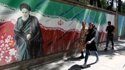 People walk past a mural painting showing the founder of the Islamic republic Ayatollah Ruhollah Khomeini and the national flag along the wall of the former US embassy in the Iranian capital Tehran on June 22, 2019. - Fear of a potential war and frustration over biting sanctions are high in Iran's capital, after a last-minute decision by the US to pull back from attacking the Islamic Republic. (Photo by ATTA KENARE / AFP)        (Photo credit should read ATTA KENARE/AFP/Getty Images)