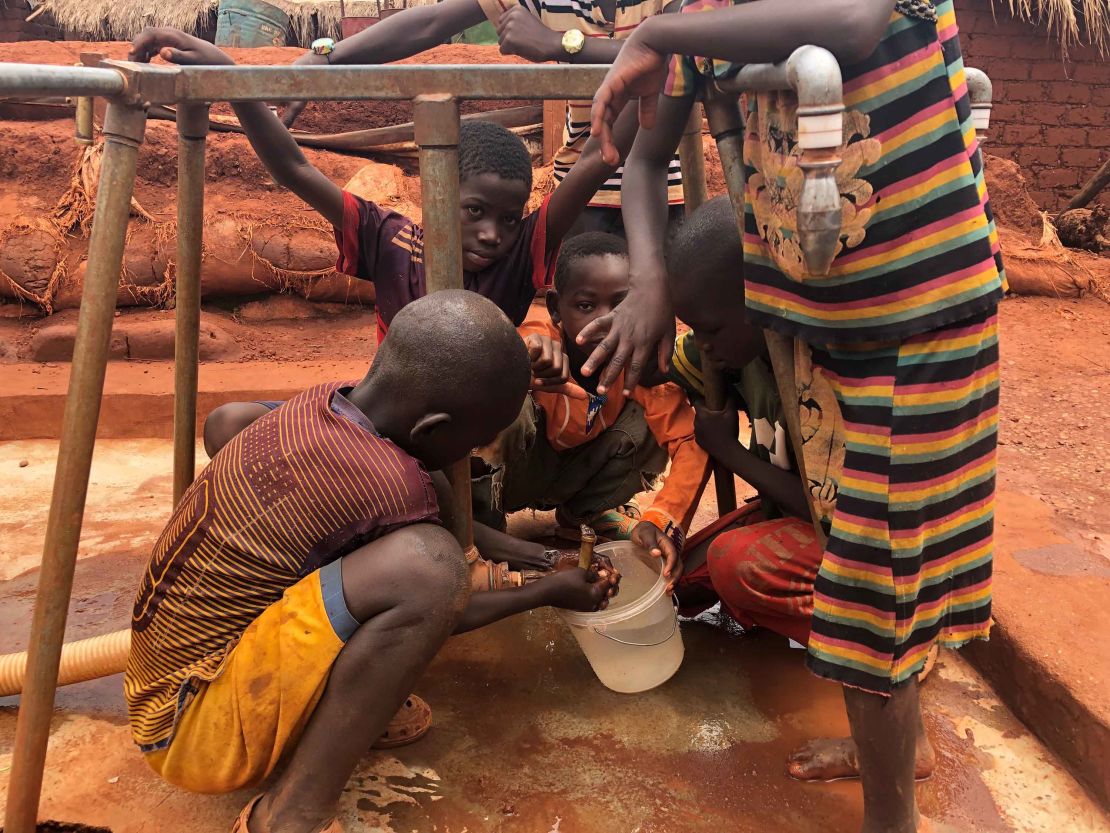 Children gather water at a filling station within the camp.