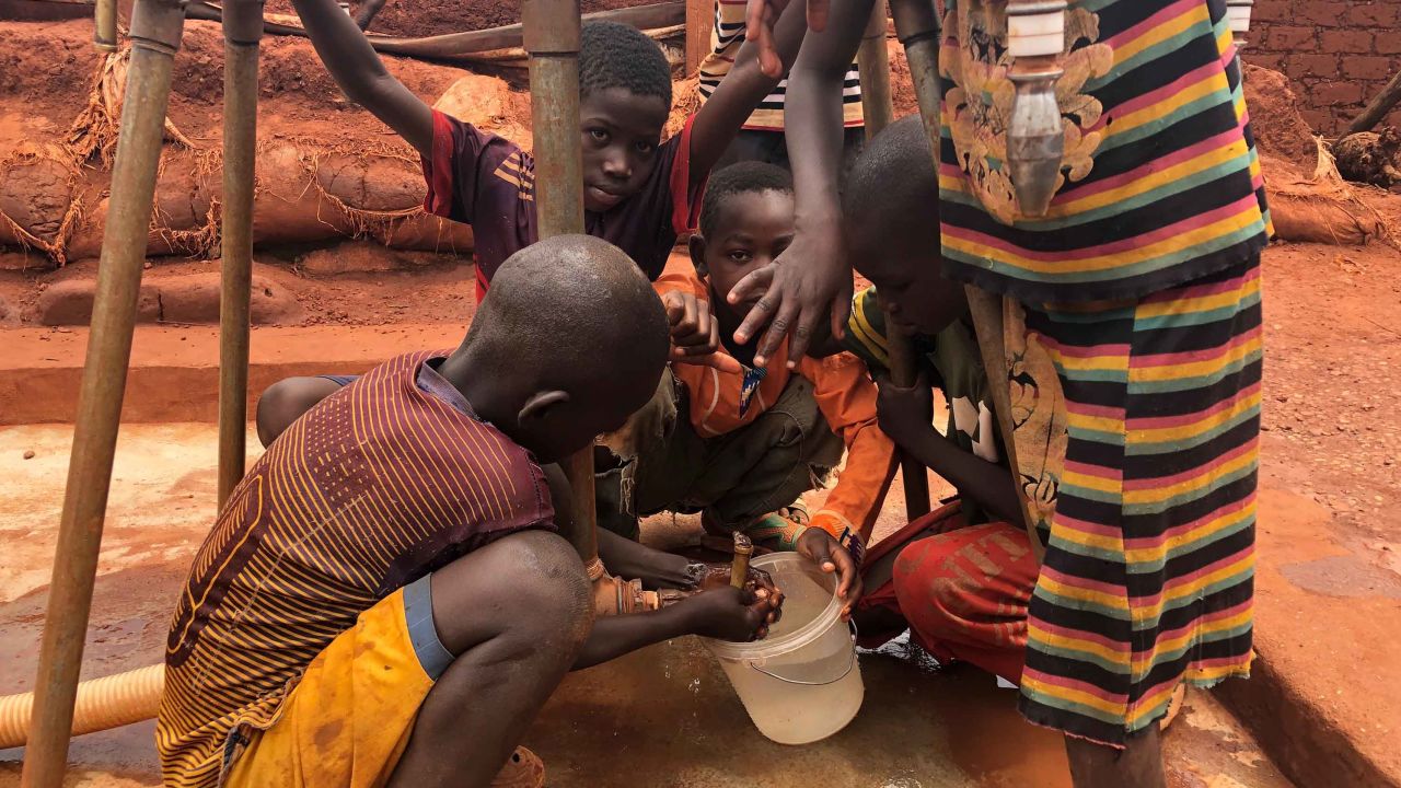 Children gather water at a filling station in the camp at Bria.