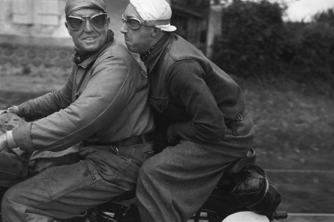 Photographers like Capa had to find ways to keep up with the Tour cyclists. A favored method was hitching a ride on a motorcycle. Here, Capa shows a press reporter and his motorcycle driver.