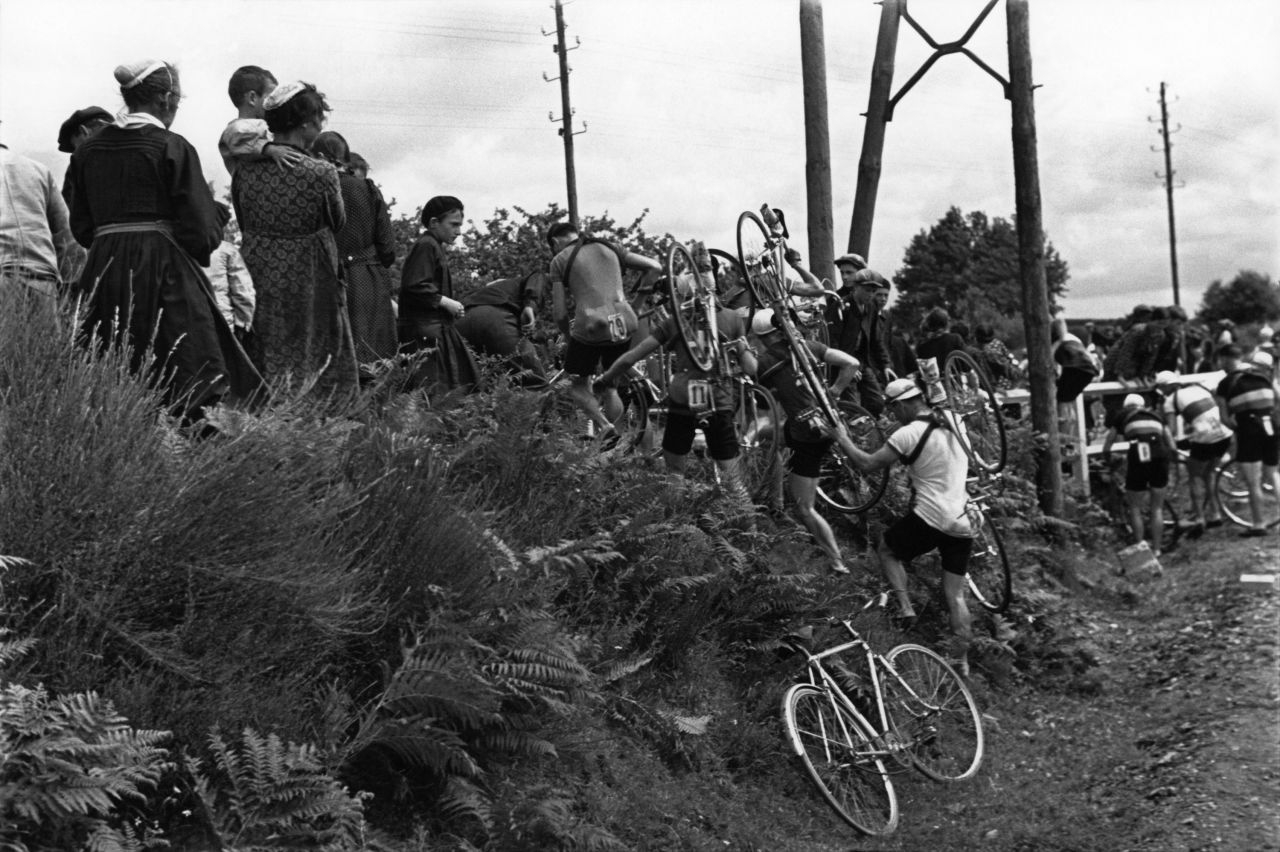 When the route was changed during the 1939 Tour, Capa was there to show the cyclists carrying their bikes over some brush — and to note the curious eyes of local residents. 