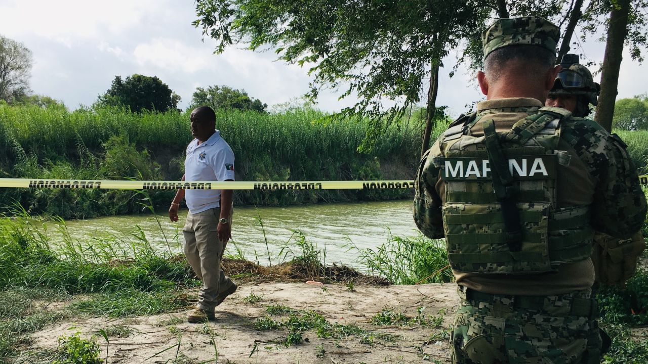 Mexican authorities walk along the Rio Grande bank where the bodies of the father and child were found.