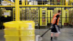 An employee pulls a pallet jack carrying plastic crates past goods in storage units at the Amazon.com Inc. fulfillment center in Robbinsville, New Jersey, U.S., on Thursday, June 7, 2018. Seattle-based Amazon hasn't yet announced the exact date for this year's Amazon Prime Day, the e-commerce giants big July sales promotion. Photographer: Bess Adler/Bloomberg via Getty Images
