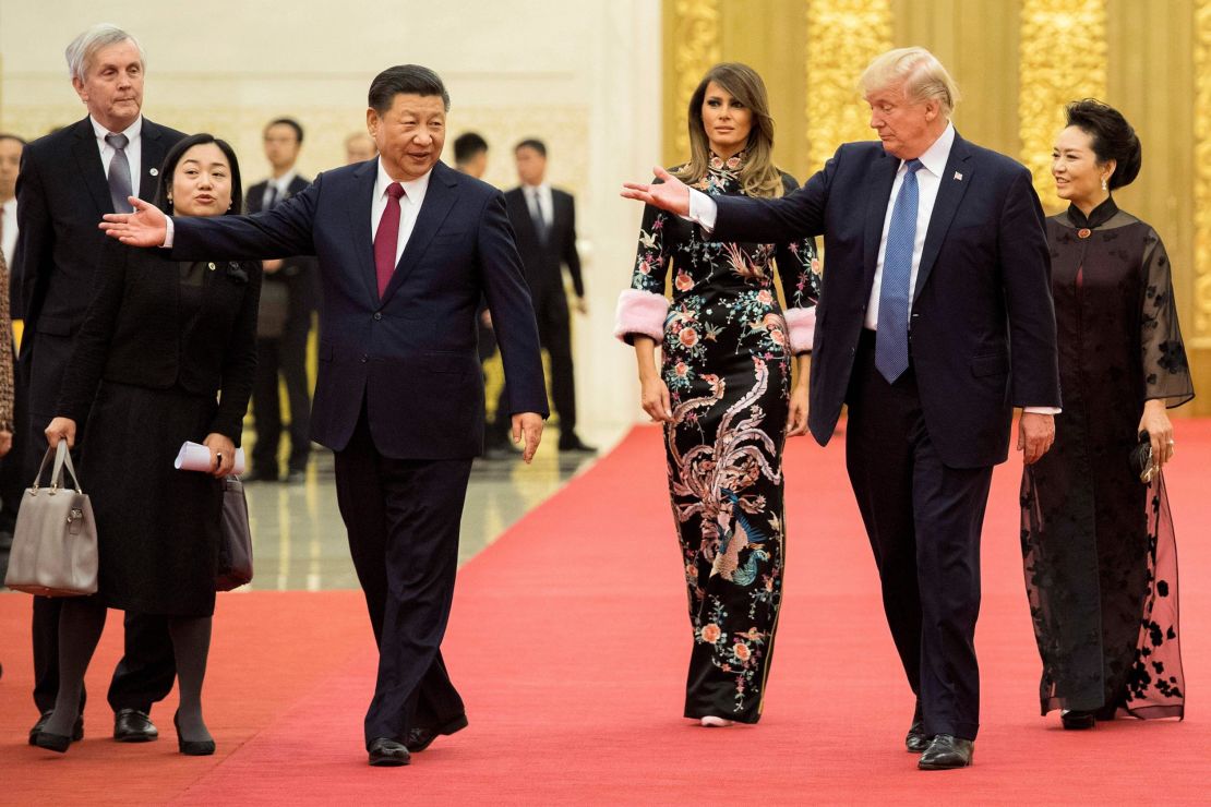 US President Donald Trump gestures toward China's President Xi Jinping, as US First Lady Melania Trump and Xi's wife Peng Liyuan look on in the Great Hall of the People in Beijing on November 9, 2017.