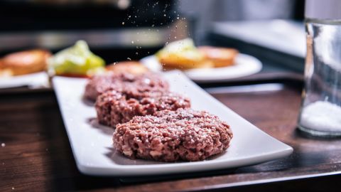 An Impossible Burger patty is seasoned in the test kitchen.