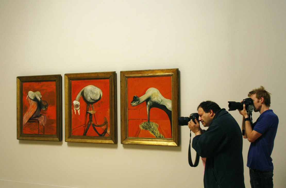 Photographers capturing "Three Studies for Figures at the Base of a Crucifixion" (1944) by Francis Bacon.