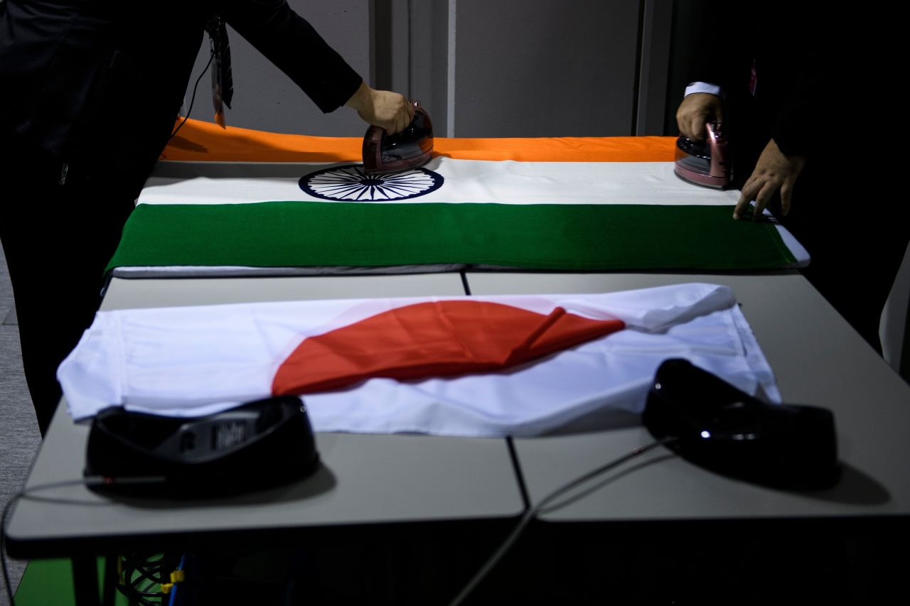Staff members prepare flags Friday for meetings during the G20 summit in Osaka.