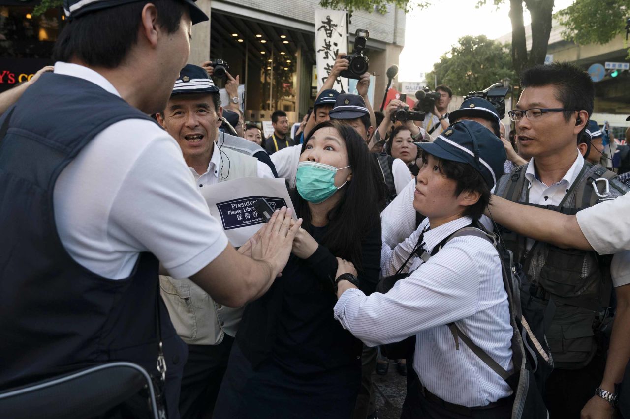 Police officers escort a pro-democracy activist Friday from a rally outside the G20 summit, where demonstrators protest against the Chinese government.