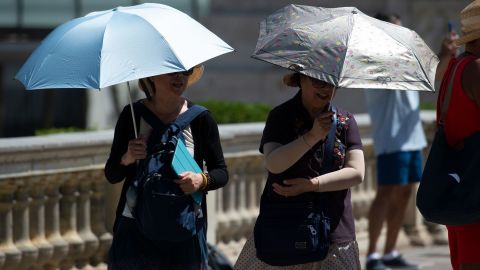 Tourists walk under umbrellas to protect themselves from the sun on a warm summer day in Barcelona on June 28.
