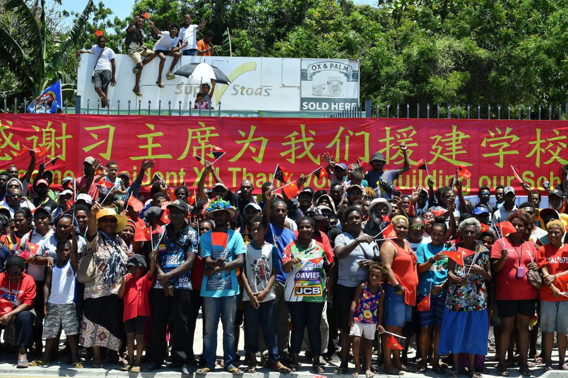 People in Papua New Guinea gather at the roadside to welcome China's President Xi Jinping in Port Moresby on November 16, 2018, ahead of the Asia-Pacific Economic Cooperation (APEC) Summit. A banner thanks Xi for building their local school. 