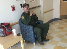 A border agent sits outside the hospital room of an 16-year-old migrant girl. 