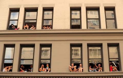 People watch from windows on 6th Avenue along the parade route.