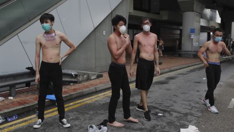 Protesters remove their shirts and try to wash their bodies after being pepper sprayed by police during protests  Monday.