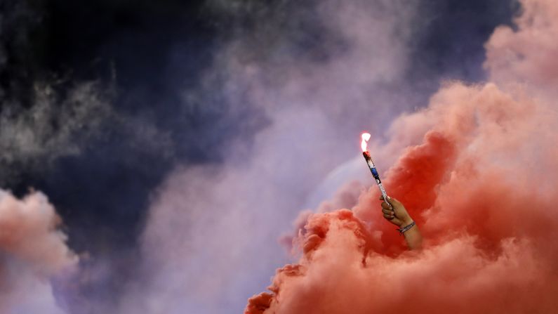 A Chivas fan holds a torch as red smoke fills the stands during the second half of the team's Colossus Cup soccer match against River Plate in San Diego, California, on Friday, June 28.