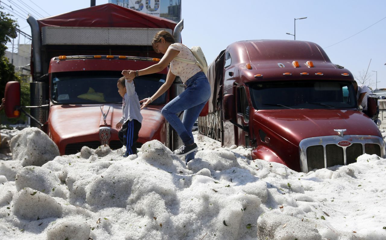 A woman and a child walk on ice in the eastern area of Guadalajara, Mexico, on Sunday, June 30. The accumulation buried some vehicles and damaged homes.
