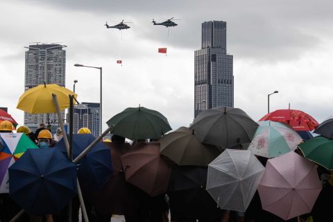 Helicopters carrying the flags of China and Hong Kong fly over demonstrators on July 1.