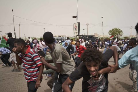 Protesters run from a police van that drove through a crowd on June 30 in Khartoum. The protesters faced off with armed forces on a main road leading to the airport.