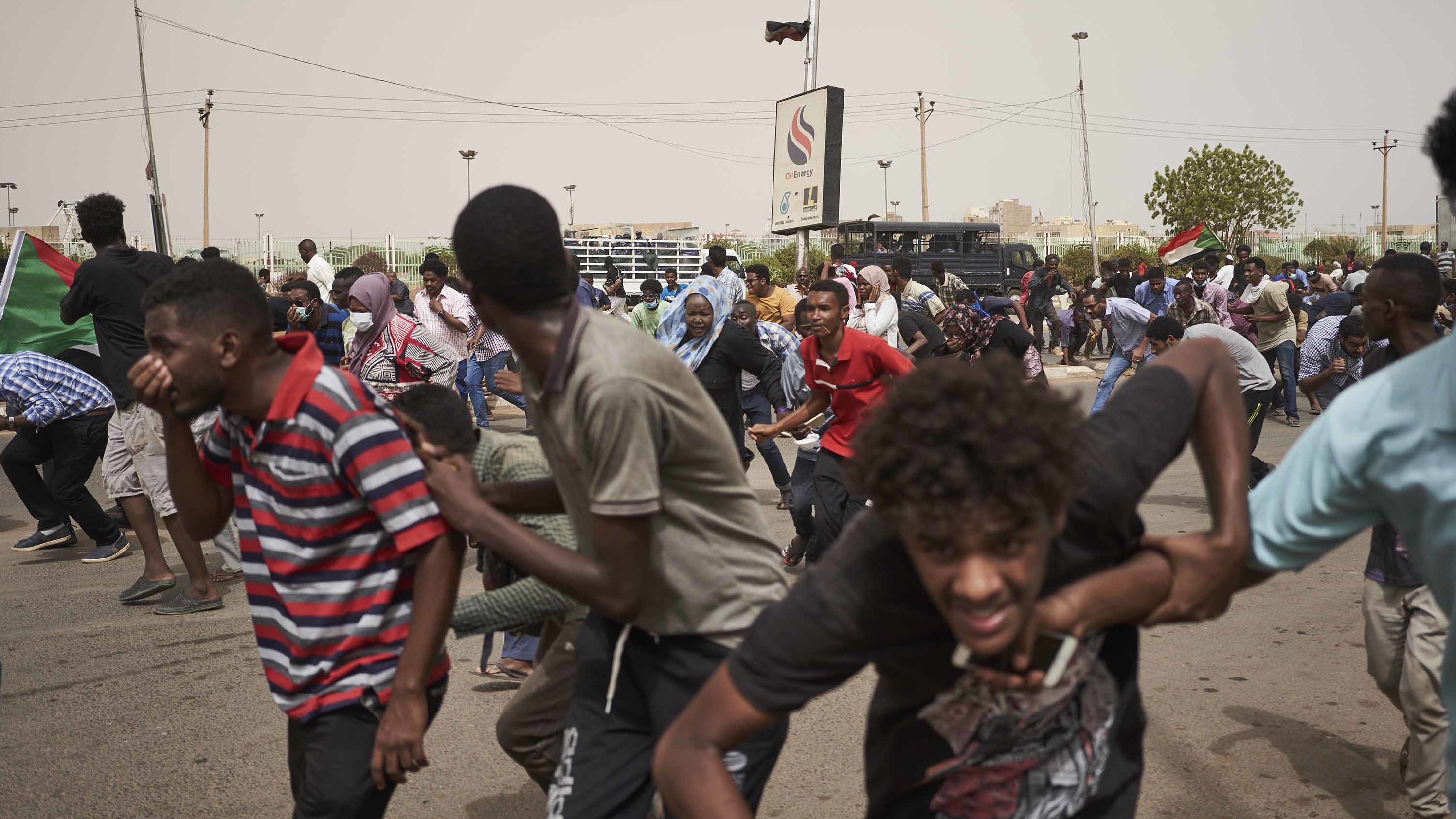 Protesters run from a police van that drove through a crowd on June 30 in Khartoum. The protesters faced off with armed forces on a main road leading to the airport.
