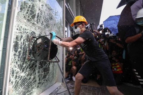 A protester smashes a window of the Legislative Council building.