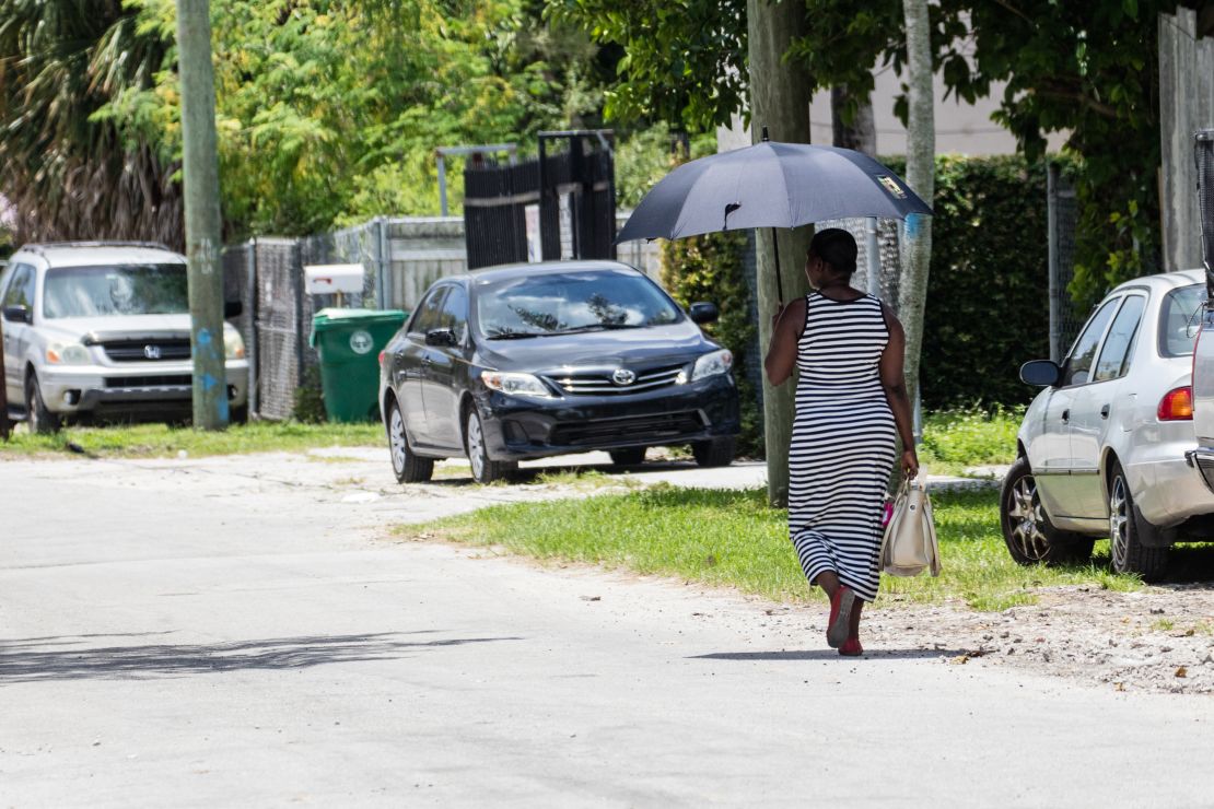 A woman uses an umbrella for shade as she walks on a hot day in Miami.