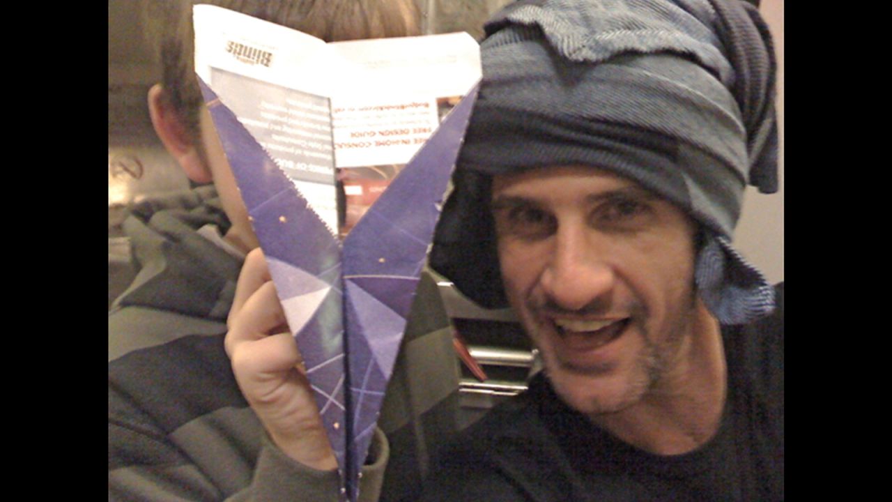 John Vlahides with a turban and paper airplane he unconsciously made while under the influence of sleeping pills.