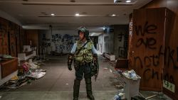 HONG KONG - JULY 2: A riot police stands near graffiti inside the Legislative Council building after it was damaged by demonstrators during a protest on July 2, 2019 in Hong Kong, China. housands of pro-democracy protesters faced off with riot police on Monday during the 22nd anniversary of Hong Kong's return to Chinese rule as riot police officers used batons and pepper spray to push back demonstrators. The city's embattled leader Carrie Lam watched a flag-raising ceremony on a video display from inside a convention centre, citing bad weather, as water-filled barricades were set up around the exhibition centre. (Photo by Anthony Kwan/Getty Images)