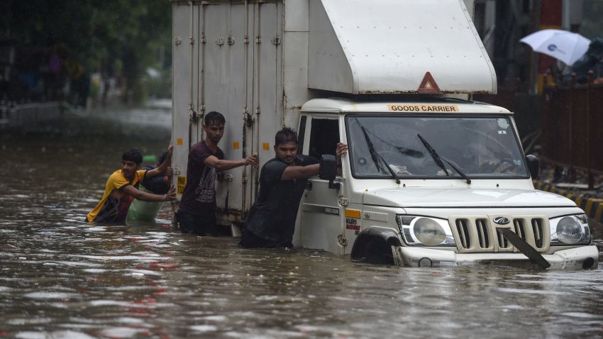 Indian men push a truck along a flooded street after heavy rain showers in Mumbai on July 1, 2019. - Heavy rains flooded parts of India's financial capital of Mumbai on July 1 as the country's four-month summer monsoon swung into full force. (Photo by PUNIT PARANJPE / AFP)        (Photo credit should read PUNIT PARANJPE/AFP/Getty Images)
