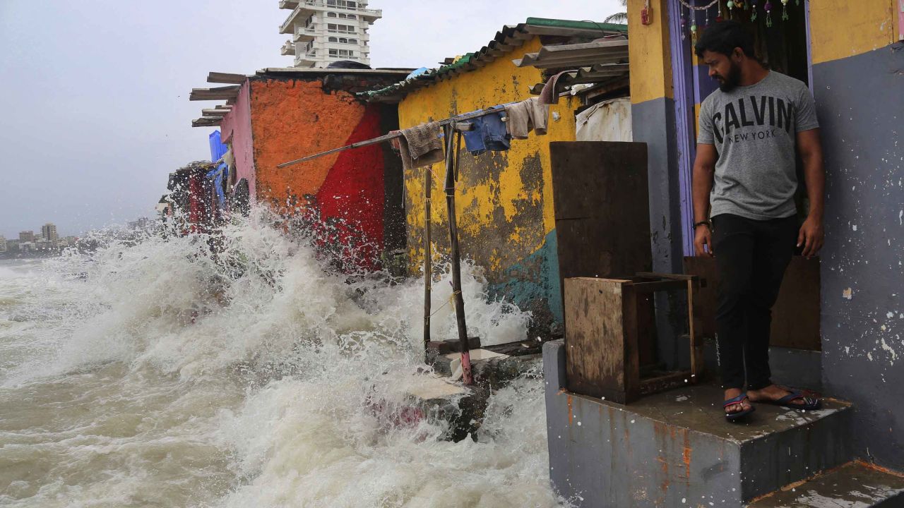 An Indian man stands near his house as waves caused by high tide hits the huts on the shore of the Arabian Sea in Mumbai, India, on July 3, 2019. 