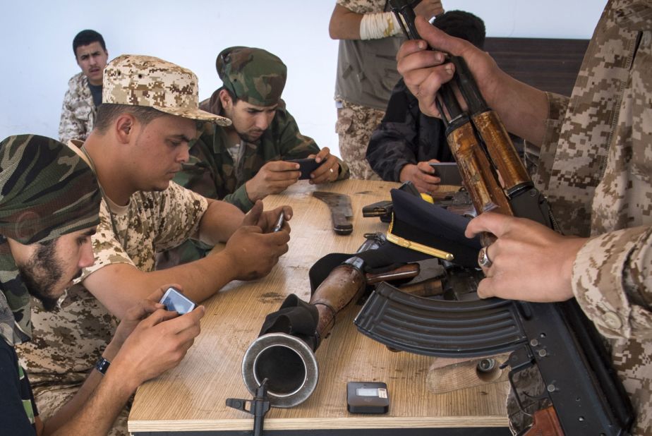 Government of National Accord forces play an online video game on their phones during a break from fighting, in a military base in Tajoura, on May 1.