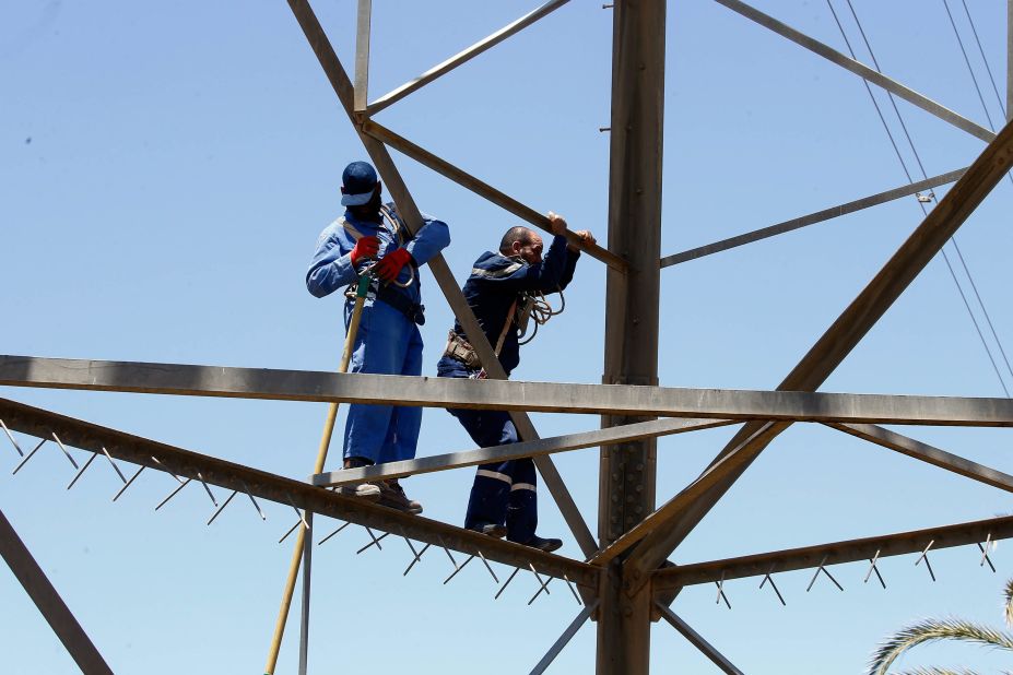 Workers operate on high voltage towers on May 23, after they were damaged by fighting.