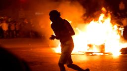 A masked Israeli member of the Ethiopian community runs past a burning barrier blocking the main entrance to Jerusalem on July 02, 2019, to protest the killing of Solomon Tekah, a young man of Ethiopian origin who was killed by an off-duty police officer. 