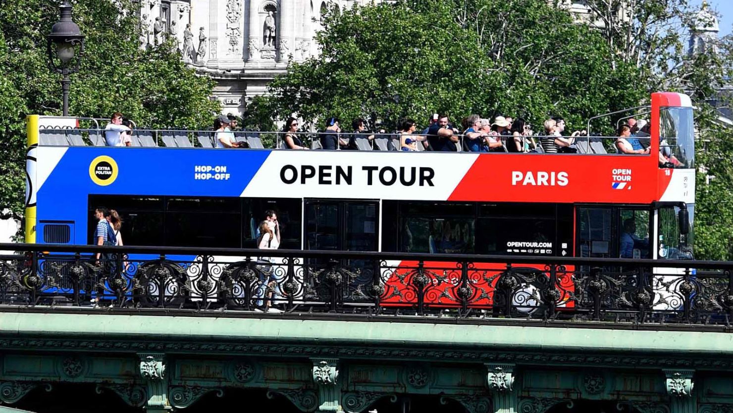 Tourists enjoy a ride on a tourist river boat (Bateaux-Mouche)and tourism bus on the Seine river on a sunny day in Paris on May 6, 2018. (Photo by GERARD JULIEN / AFP)        (Photo credit should read GERARD JULIEN/AFP/Getty Images)