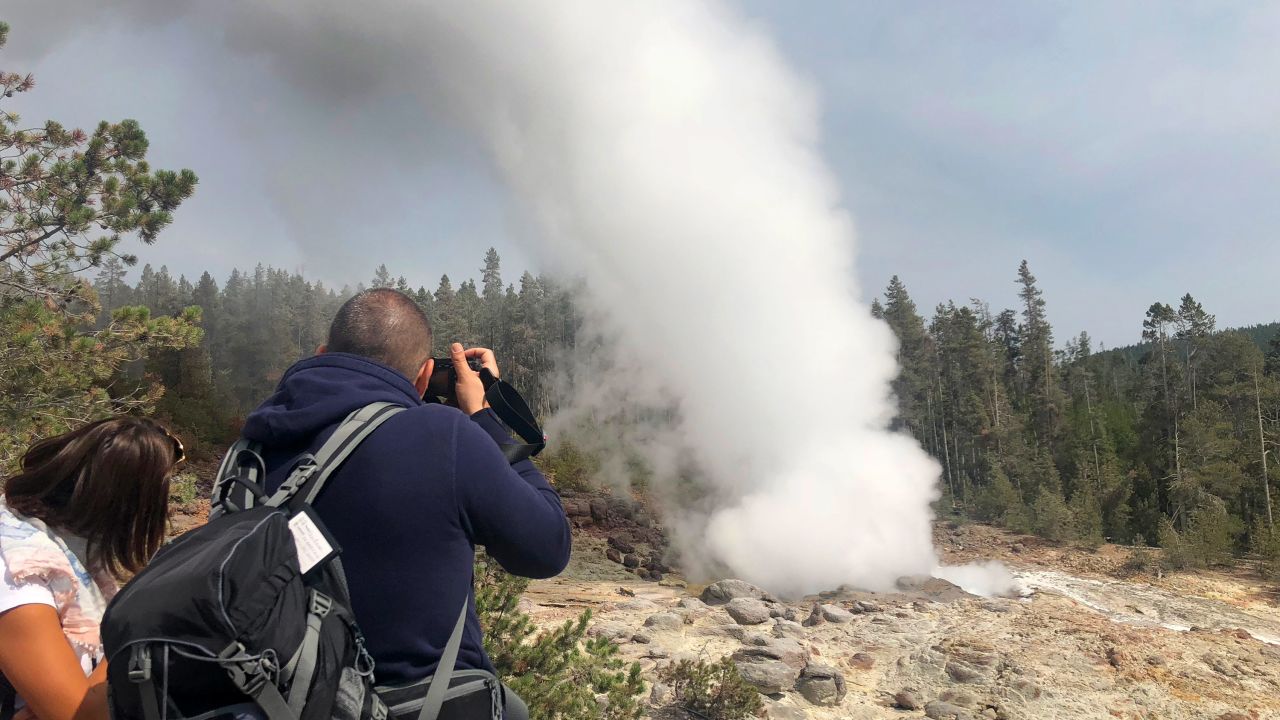Tourists watch the Steamboat Geyser erupt on August 22, 2018 in Yellowstone National Park.
