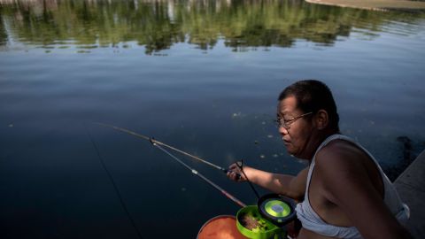 A man sports a so-called Beijing bikini as he fishes by Houhai Lake in Beijing on July 1, 2019. 