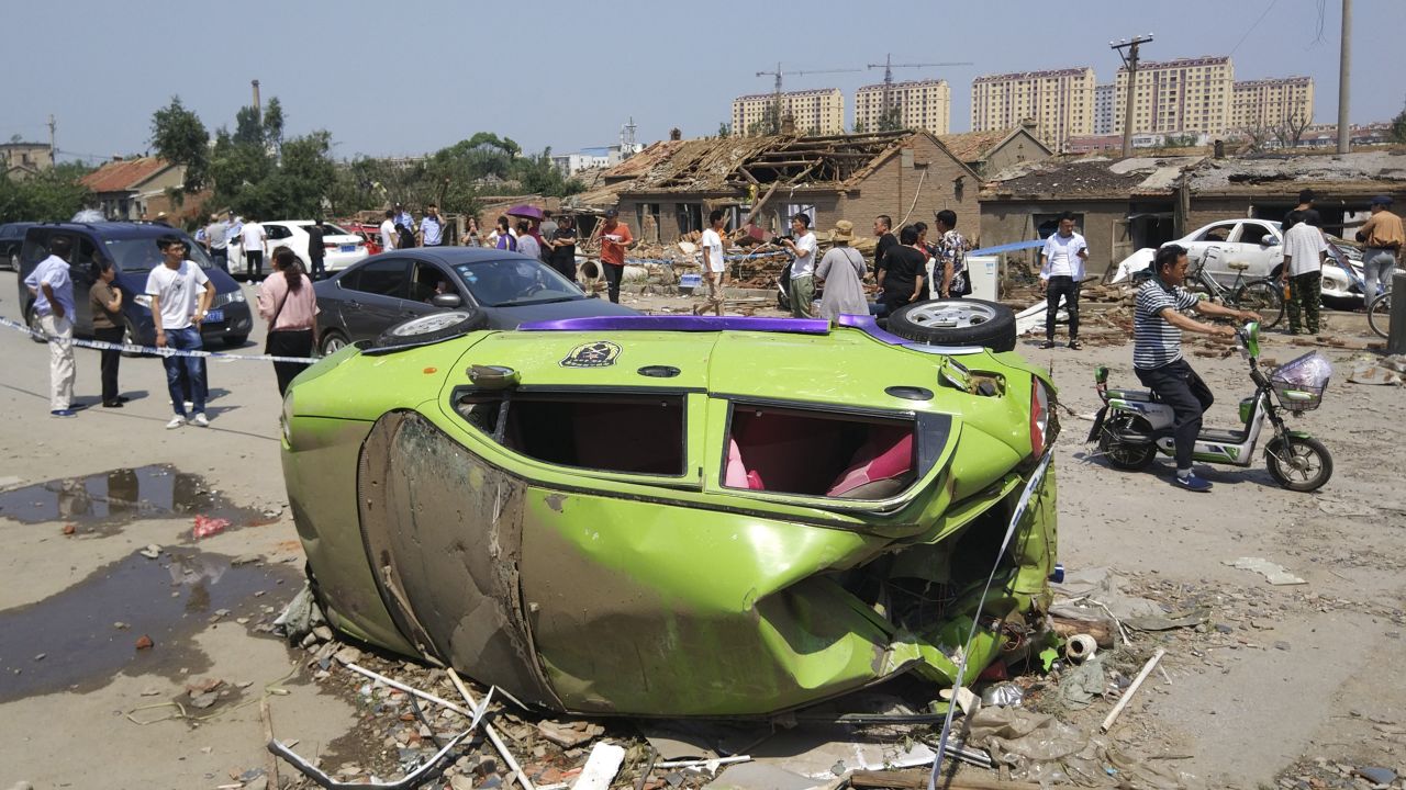 Residents pass by an overturned car in the aftermath of the tornado.