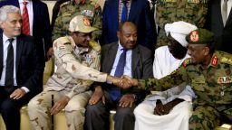 African union envoy to Sudan Mohamed al-Hacen Lebatt (L) sits next to Sudan's deputy chief of the ruling military council General Mohamed Hamdan Dagalo as he shakes hands with an army general following a press conference in Khartoum in which they announced ruling generals and protest leaders have reached an agreement on the disputed issue of a new governing body on July 5, 2019. - The landmark agreement came after two days of talks following the collapse of the previous round of negotiations in May over who should lead the new ruling body -- a civilian or soldier. "The two sides agreed on establishing a sovereign council with a rotating military and civilian (presidency) for a period of three years or little more," African Union mediator Mohamed El Hacen Lebatt told reporters.