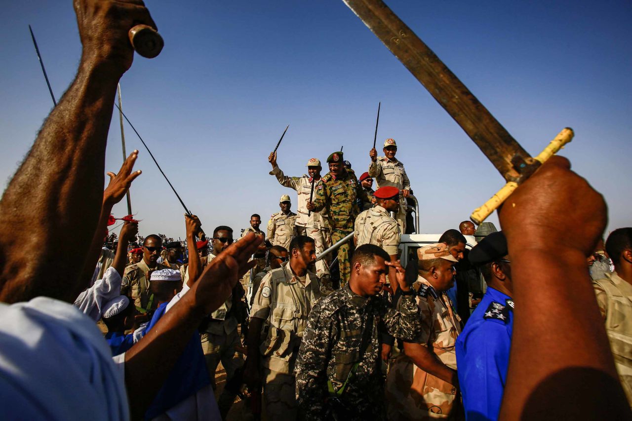 Mohamed Hamdan Dagalo, deputy head of Sudan's ruling Transitional Military Council (TMC) and commander of the Rapid Support Forces (RSF) paramilitaries, center right, waves a baton as he rides through supporters in Qarri, north of Khartoum, on June 15.