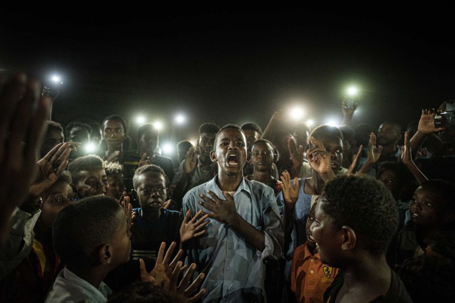 People chant slogans as a young man recites a poem, illuminated by mobile phones on June 19.